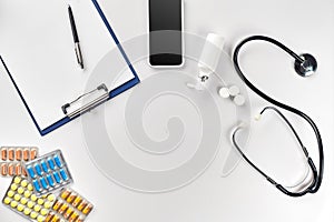 Stethoscope in the office of doctors.Top view of doctor`s desk table, blank paper on clipboard with pen. Copy space