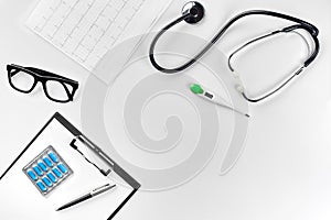 Stethoscope in the office of doctors.Top view of doctor`s desk table, blank paper on clipboard with pen. Copy space