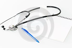Stethoscope in the office of doctors.Top view of doctor`s desk table, blank paper on clipboard with pen. Copy space