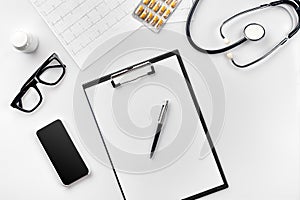 Stethoscope in the office of doctors.Top view of doctor`s desk table, blank paper on clipboard with pen. Copy space