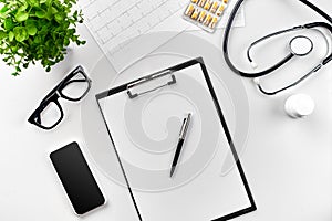 Stethoscope in the office of doctors. Top view of doctor`s desk table, blank paper on clipboard with pen. Copy space