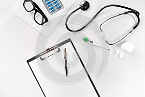 Stethoscope in the office of doctors.Top view of doctor`s desk table, blank paper on clipboard with pen. Copy space