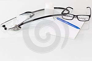 Stethoscope in the office of doctors.Top view of doctor`s desk table, blank paper on clipboard with pen. Copy space