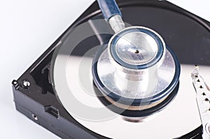 Stethoscope on old dusty disassembled hard drive from the computer over dark background