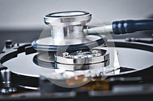 Stethoscope on old dusty disassembled hard drive from the computer over dark background