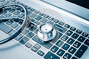 Stethoscope over a computer keyboard toned in blue