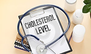 Stethoscope and paper note with text CHOLESTEROL LEVEL. Health concept