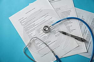 Stethoscope and patient medical history on color background. Health care concept