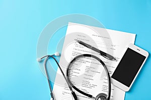Stethoscope with patient medical history and phone on color background. Health care concept