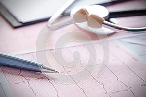 Stethoscope with pen glasses, magnifier and cardiogram and other medicine equipment lay on a table