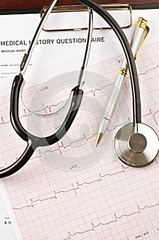 Stethoscope and pen over questionnaire and cardiogram