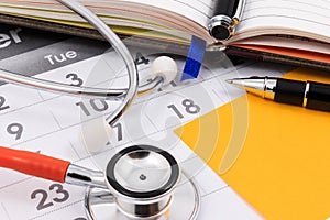 Stethoscope, pen and paper note on calendar, doctor appointment. photo