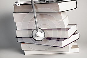 Stethoscope on pile of books isolated. Blue background