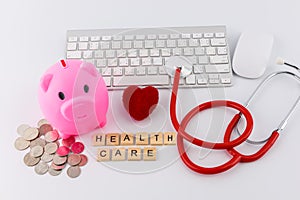 Stethoscope with piles of coins, red heart, piggy bank, saving f