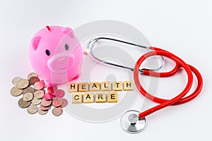 Stethoscope with piles of coins, red heart, piggy bank, saving f