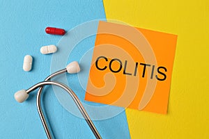 Stethoscope, pill capsules and orange note with text COLITIS