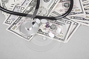 Stethoscope and pills on American Dollars