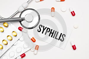 Stethoscope, pills and notebook with Syphilis word on medical desk