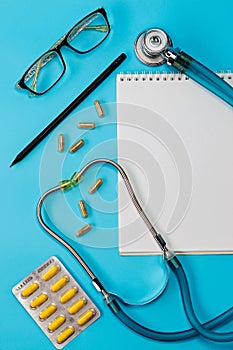 Stethoscope, pills, pen, notebook on the doctor desk