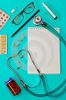 Stethoscope, pills, pen, notebook on the doctor desk