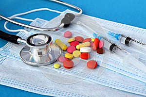 Stethoscope pills and syringes lie on medical masks.