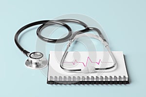 Stethoscope and Pulse Heartbeat Notebook Still Life Object on Blue Background