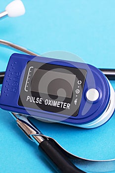 Stethoscope and pulse oximeter on blue background