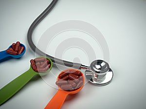 Stethoscope and red capsules pills on colorful measuring spoon on white background.