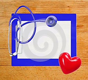 Stethoscope, red heart and blue clipboard over wooden