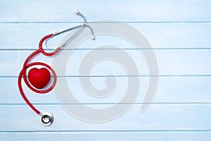 Stethoscope and red heart on blue wooden background