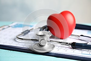 Stethoscope, red heart and cardiogram on table. Cardiology photo