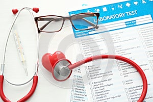 Stethoscope with red heart and lists of laboratory tests on white background.  Health care concept