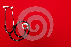 Stethoscope and red heart on red background with copy space. Space for text