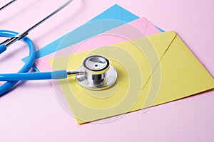 Stethoscope and several colored envelopes on pink background doctor`s day, health care day concept
