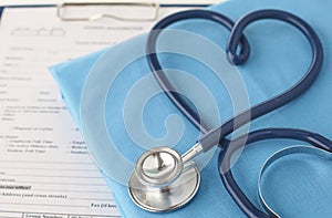 A stethoscope shaping a heart and a clipboard on a medical uniform, closeup