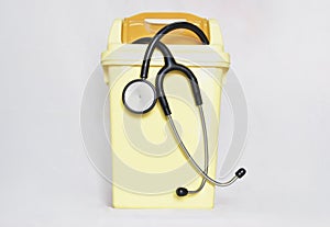 Stethoscope in Small Yellow Plastic Trash Can. Shows Quit the Medical Job, Disappoint and Give up Doctor Profession