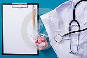 Stethoscope, sweets, notepad, pen, folded form of a doctor lie on the table