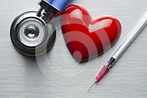 Stethoscope, syringe and figurine in the shape of a heart photo