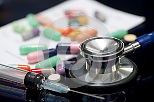 Stethoscope, Syringe, Medications, And Written Prescription On Dark Surface