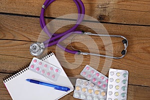 Stethoscope and tablets isolated on wooden background