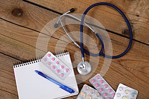 Stethoscope and tablets isolated on wooden background