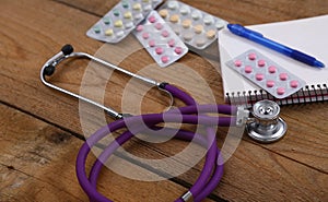 Stethoscope and tablets isolated on wooden background