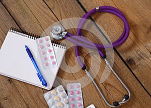 Stethoscope and tablets isolated on wooden background