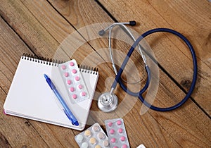 Stethoscope and tablets isolated on wooden background