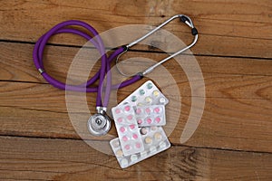 Stethoscope and tablets isolated on wooden background