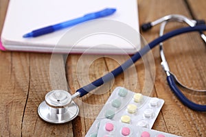 Stethoscope and tablets isolated on wooden background