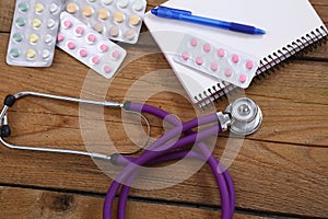 Stethoscope and tablets isolated on wooden background