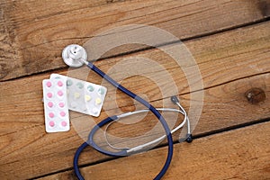 Stethoscope and tablets isolated on wooden background