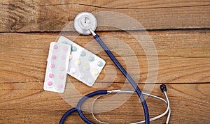 Stethoscope and tablets isolated on wooden background