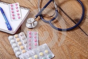 Stethoscope and tablets isolated on wooden background